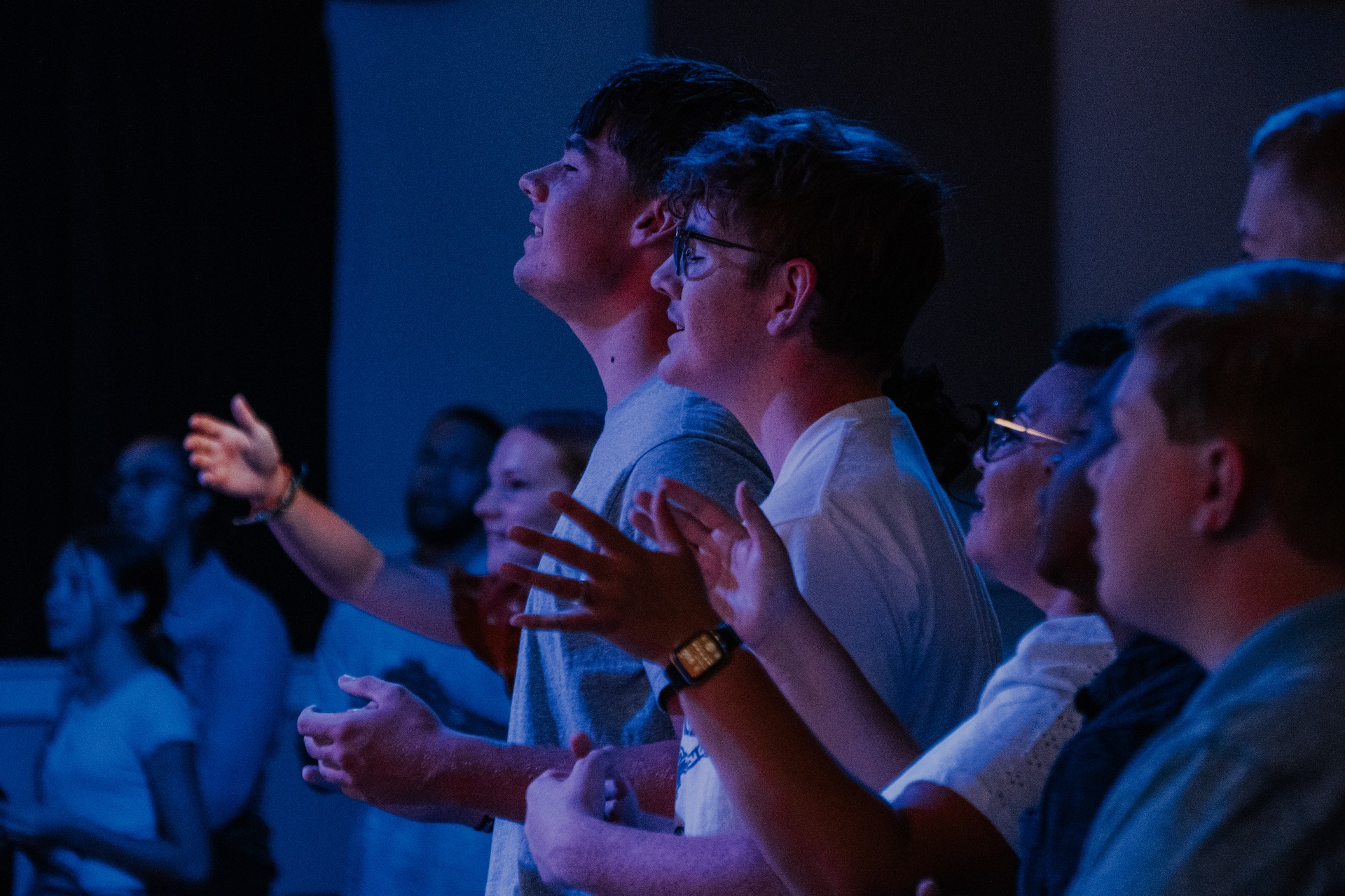 A Group Of Young Worshippers In A Church, Hands Raised High, Celebrating Together